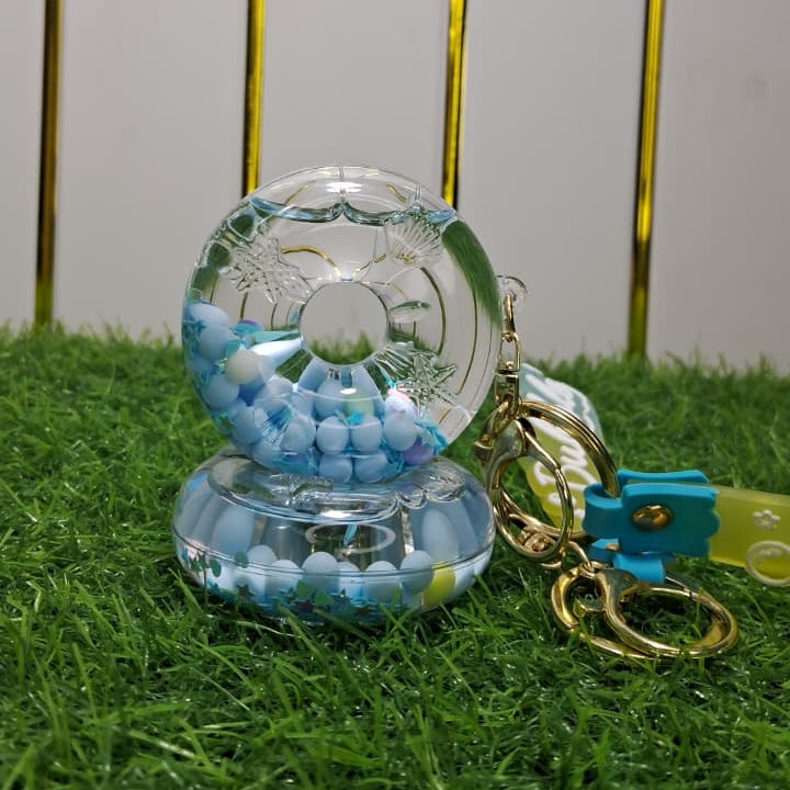 Clear glass ornament with blue beads on a grassy surface with gold poles in the background
