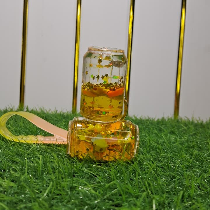 Two small glass jars with colorful contents on a grassy surface with a metal chair in the background.