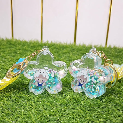 Two clear keychains with glittery accents on a grassy surface.