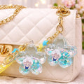 Decorative keychains with cartoon characters on a white quilted handbag.